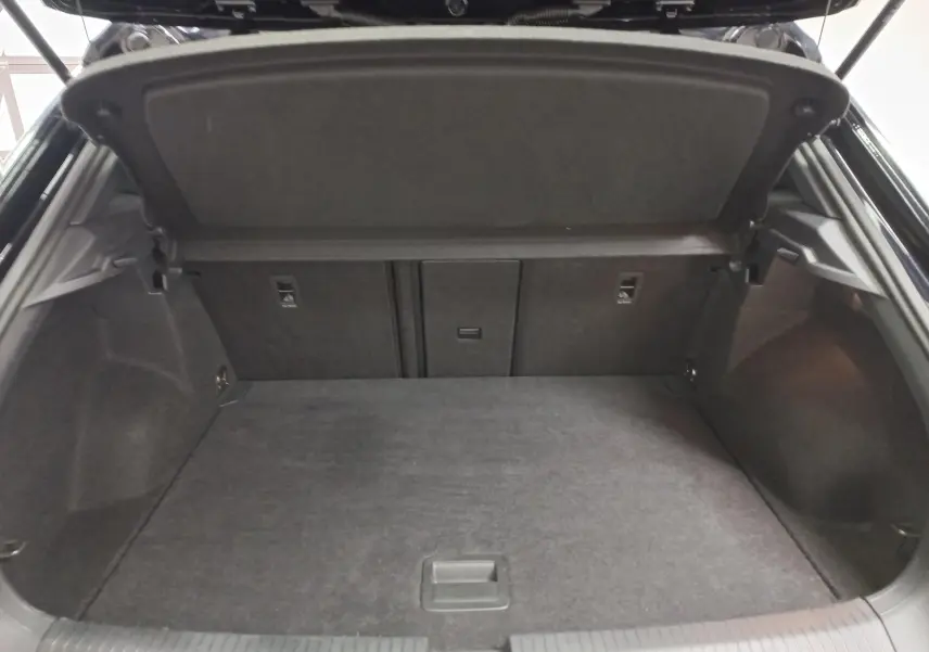 Vue intérieure du coffre ouvert d'un Volkswagen T-Roc 2025 noir intense, montrant un espace de chargement propre et spacieux.