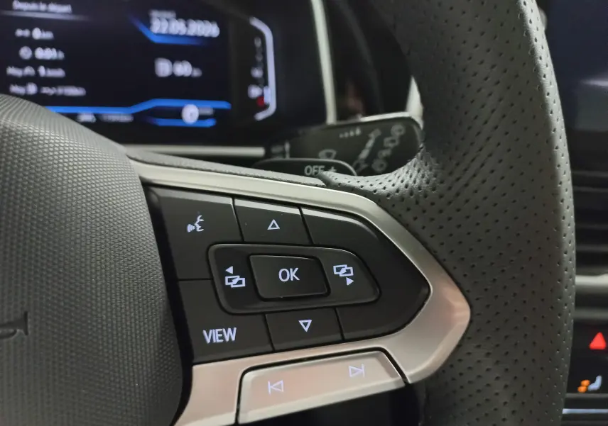 Gros plan sur le volant en cuir perforé du Volkswagen T-Roc 2025 avec commandes multifonctions éclairées.