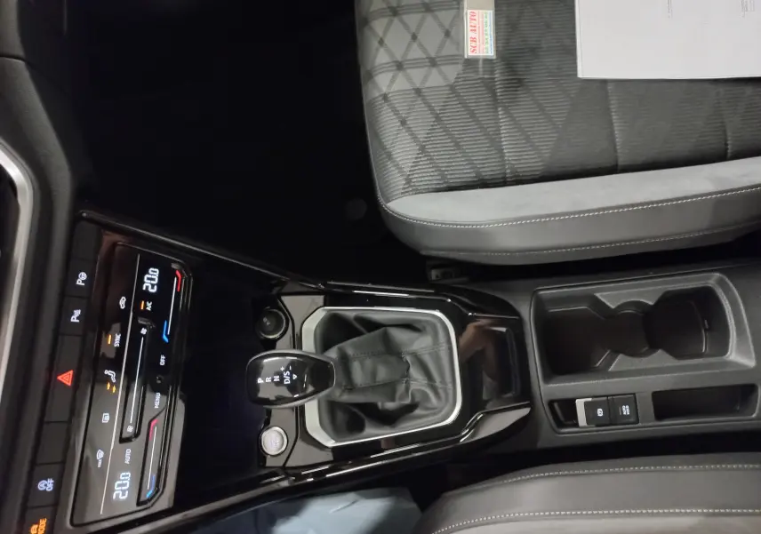 Vue intérieure centrée sur la console centrale et levier de vitesse du Volkswagen T-Roc noir intense 2025.