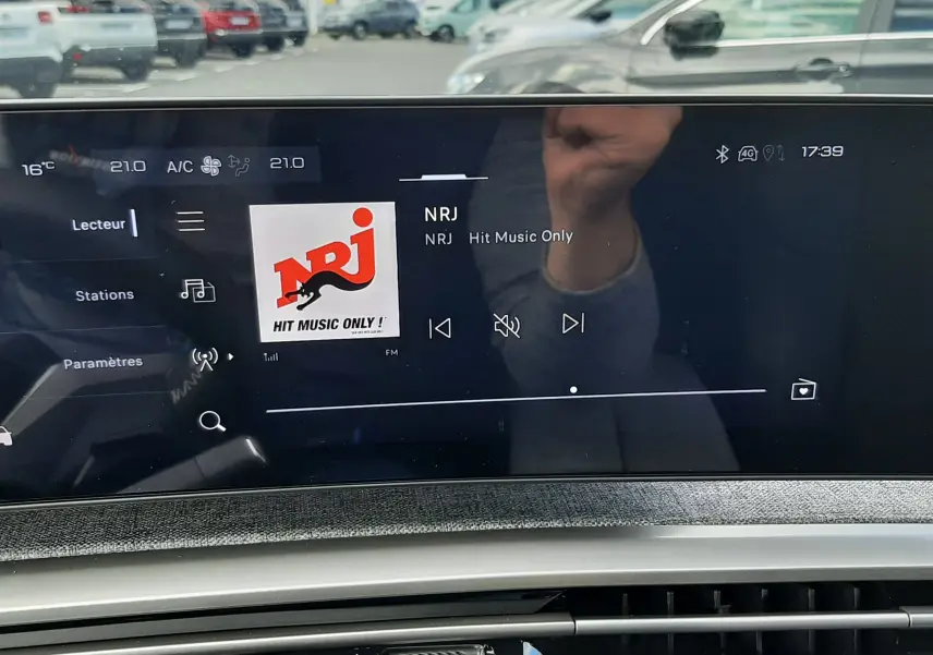 Écran central tactile du Peugeot 3008 gris titane, affichant la radio NRJ en extérieur, vue intérieure avant.