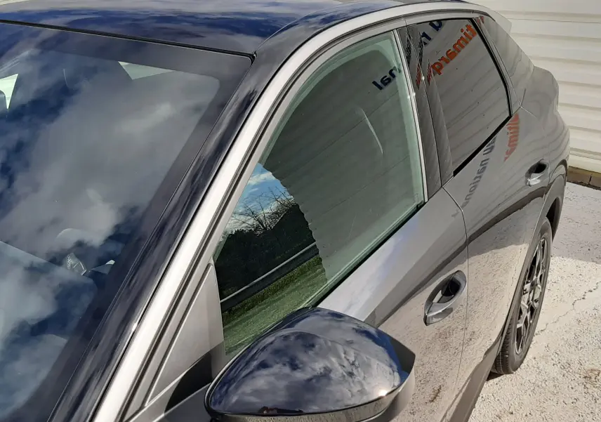 Vue de côté droit avant du Peugeot 3008 gris titane avec toit noir brillant et rétroviseur assorti.