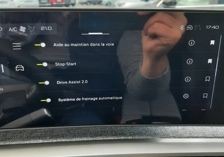 Écran tactile intérieur du Peugeot 3008 2026 affichant les options d’aide à la conduite avec reflet de la main.