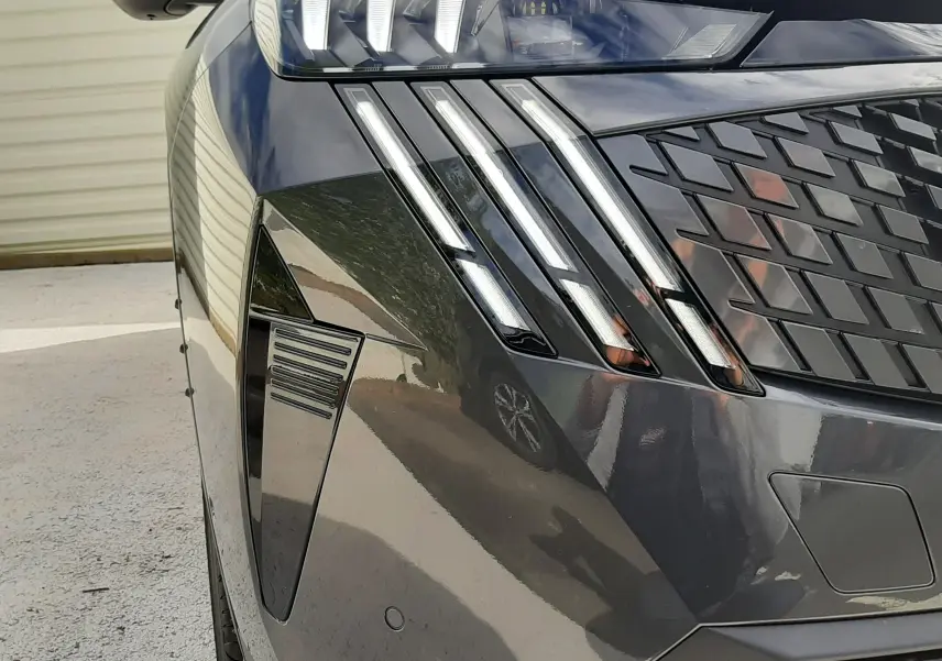 Gros plan sur l'avant droit du Peugeot 3008 gris titane avec feux LED et calandre au design moderne.
