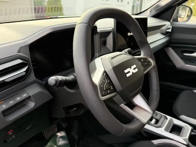 Vue intérieure du volant multifonction du Dacia Duster 1.8 Hybrid 155 Journey, avec tableau de bord moderne et sellerie spécifique.