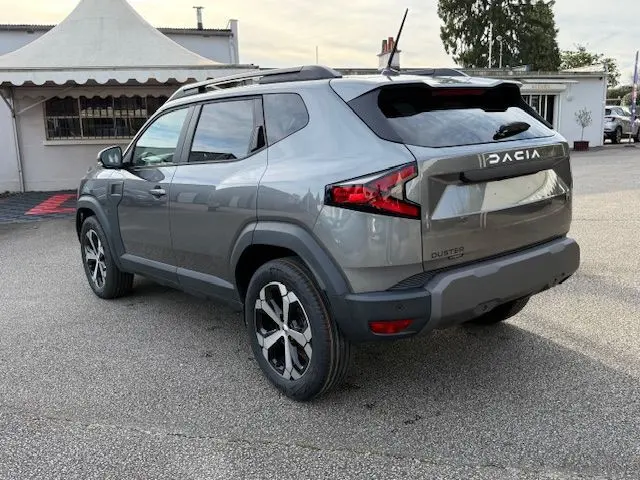 Vue 3/4 arrière droite du Dacia Duster 1.8 Hybrid 155 Journey gris schiste avec jantes biton et sellerie spécifique.