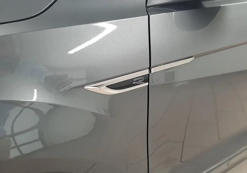 Détail de l'aile avant gauche gris Indium du Volkswagen T-Roc 1.5 TSI R-Line avec logo R chromé.