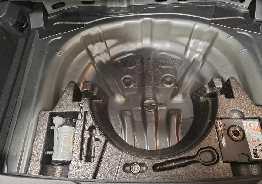 Coffre ouvert en vue plongeante du Volkswagen T-Roc 2025, montrant le rangement sous plancher sans roue de secours.