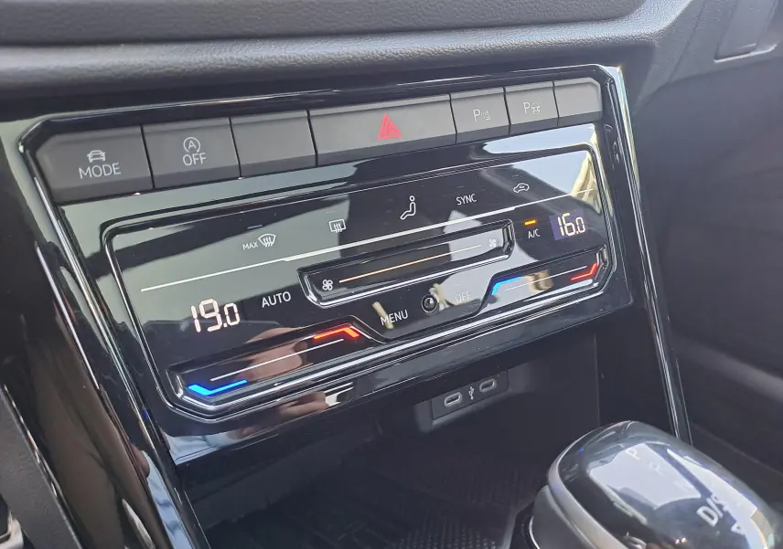 Gros plan sur la console centrale du Volkswagen T-Roc 2025, affichage numérique de la climatisation automatique.