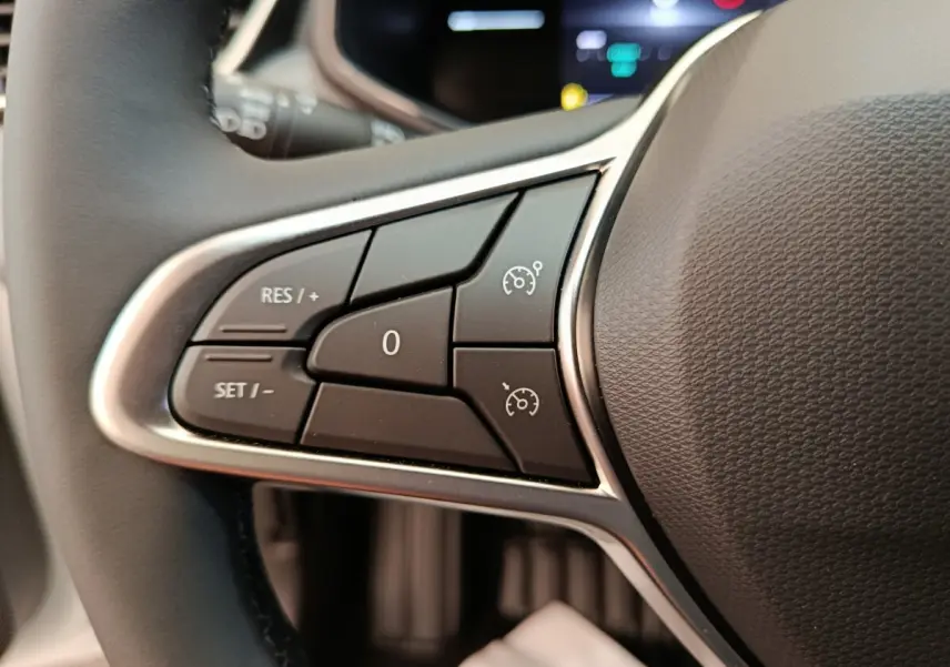 Gros plan sur les commandes du régulateur de vitesse au volant cuir de la Renault Clio blanche 2024.