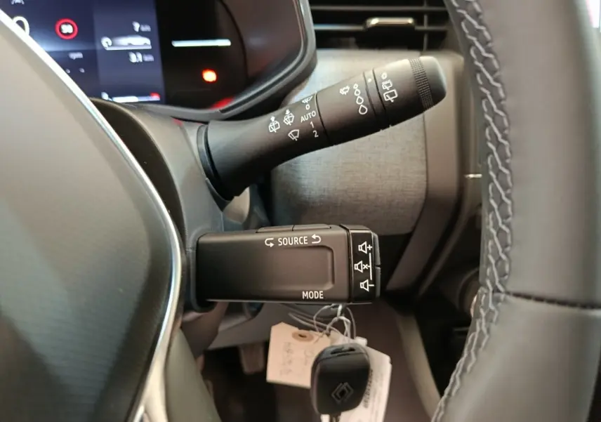 Gros plan sur les commandes au volant et le combiné d'instruments d'une Renault Clio blanche 2024, intérieur moderne.