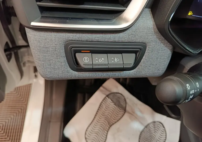 Détail des commandes d’éclairage et verrouillage sur tableau de bord gris clair d’une Renault Clio blanche 2024.