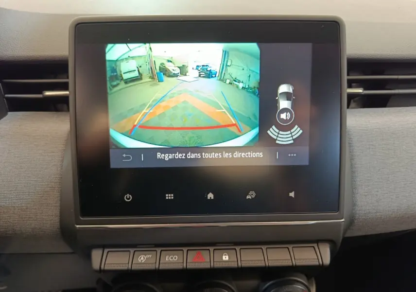 Écran tactile central montrant la caméra de recul et l’aide au stationnement dans un Renault Clio blanc, vue intérieure.