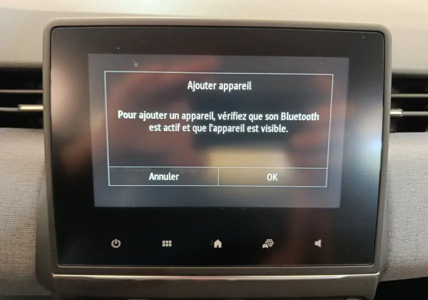 Écran tactile central de la Renault Clio blanche 2024 affichant un message d'ajout d'appareil Bluetooth.
