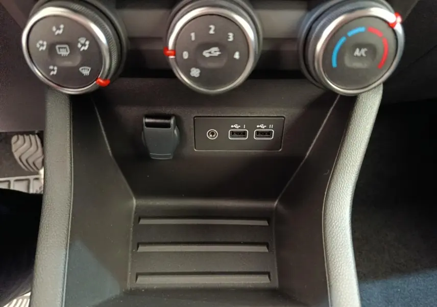 Vue rapprochée de la console centrale noire de la Renault Clio 2024 montrant les commandes de climatisation et ports USB.