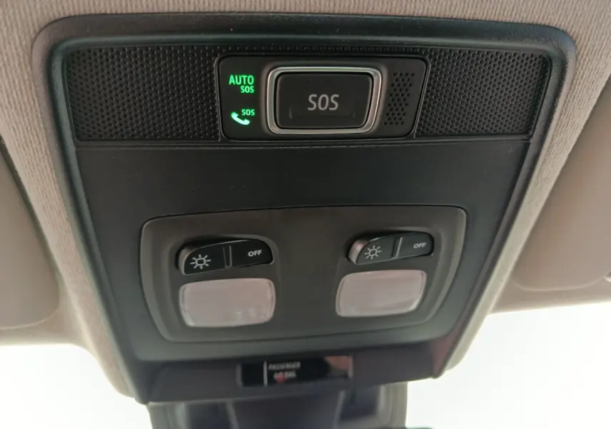 Vue en contre-plongée du panneau de commande de plafonnier noir avec bouton SOS éclairé dans une Renault Clio blanche 2024.