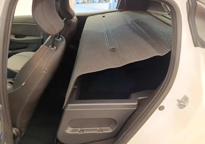 Vue intérieure côté droit de la Renault Clio blanche 2024 montrant la banquette arrière rabattue et le coffre sous la tablette.