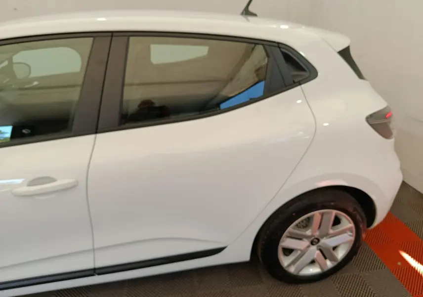 Vue latérale côté droit d'une Renault Clio blanche 2024, mettant en valeur la porte arrière et la roue arrière.