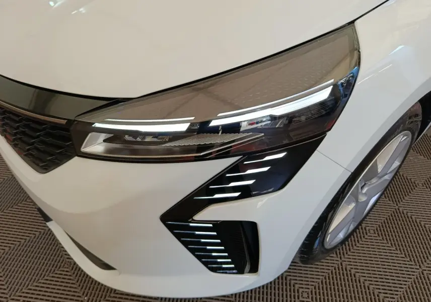 Gros plan sur l'avant droit blanc de la Renault Clio 2024, mettant en valeur les phares LED et la calandre noire.