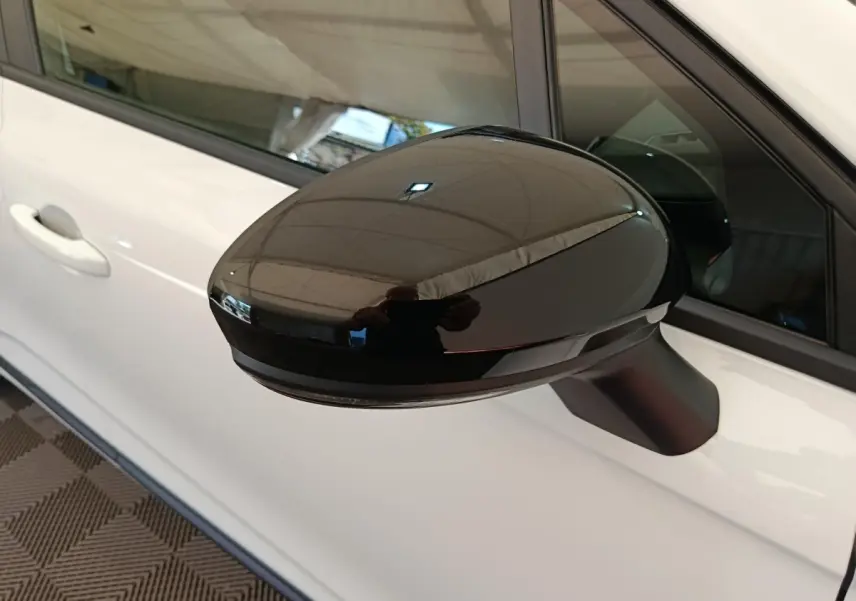 Rétroviseur noir en gros plan côté gauche d’une Renault Clio blanche 2024 avec poignée de porte visible.