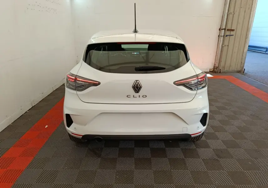Vue arrière d'une Renault Clio blanche 2024 avec feux LED et logo centré dans un garage.
