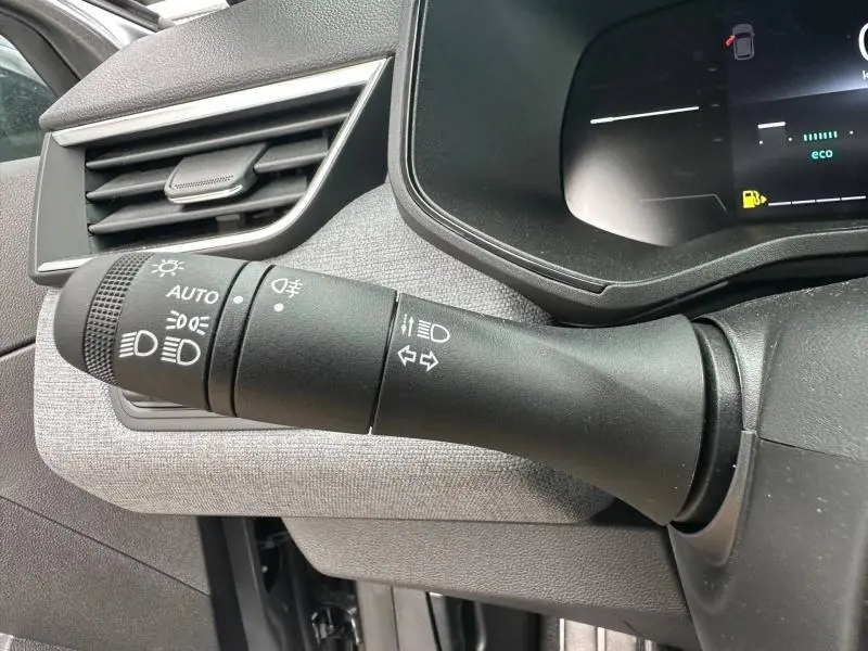 Gros plan sur la commande des feux et clignotants du tableau de bord d'une Renault Clio 2025, intérieur gris.