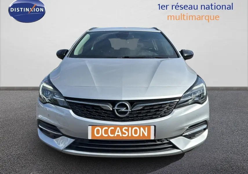 Vue frontale d'une Opel Astra Sports Tourer gris minéral métal avec calandre noire et phares LED allumés.