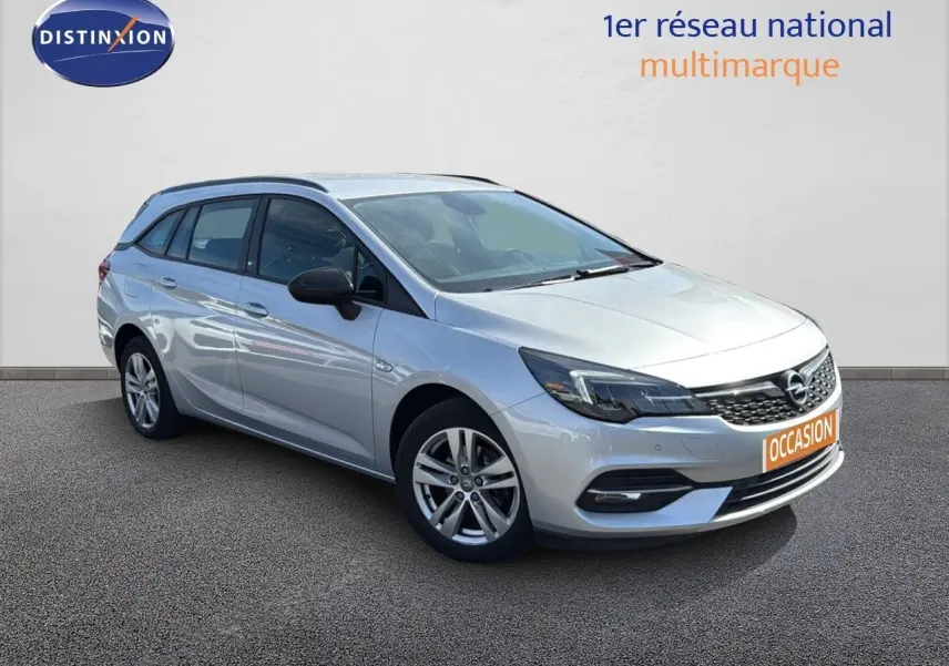 Opel Astra Sports Tourer gris minéral métal vue 3/4 avant droit avec calandre noire et jantes alliage.
