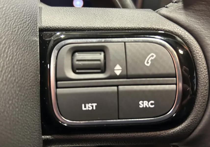 Gros plan sur les commandes au volant du Citroën C5 Aircross 2025, finition cuir noir et détails chromés.