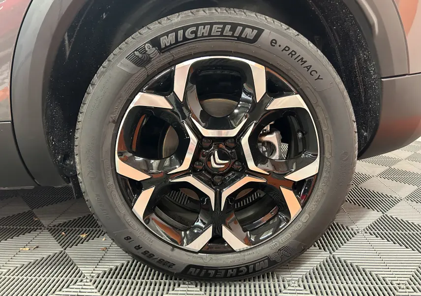 Gros plan sur la roue avant droite d'un Citroën C5 Aircross gris platinium avec jante alliage bicolore et pneu Michelin.