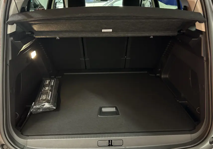 Coffre ouvert du Citroën C5 Aircross gris platinium 2025, montrant un espace de chargement propre avec kit d'assistance visible à gauche.