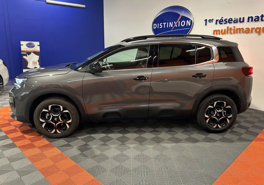 Profil côté gauche d'un Citroën C5 Aircross gris platinium 2025 dans un showroom avec jantes bi-ton.