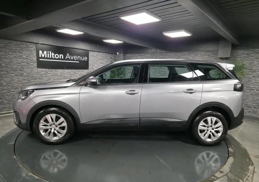 Profil côté gauche du Peugeot 5008 gris métallisé, SUV familial 7 places en intérieur showroom.
