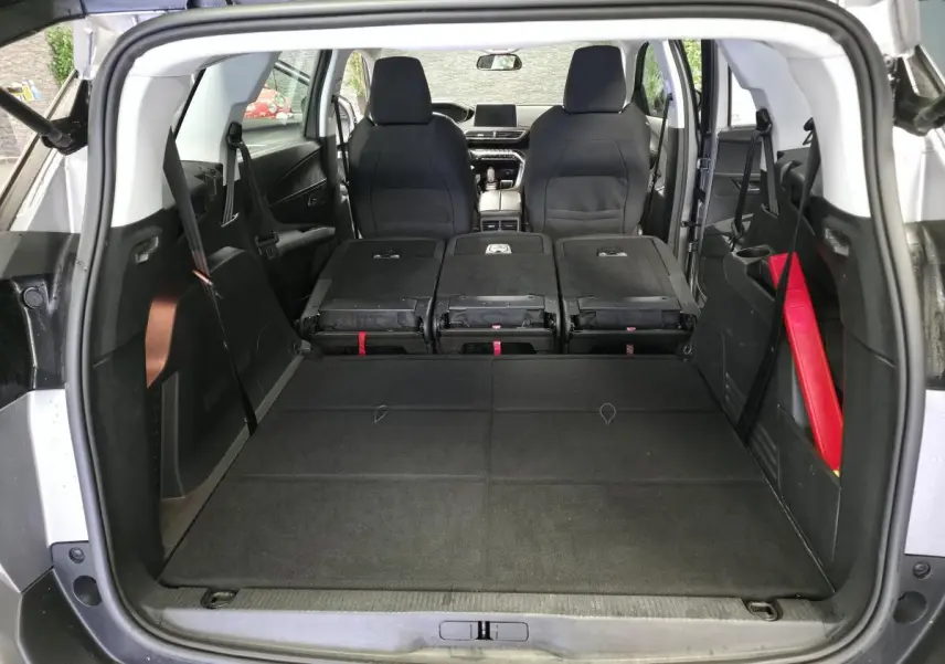 Vue arrière du coffre du Peugeot 5008 gris avec sièges arrière rabattus et intérieur spacieux visible jusqu'aux sièges avant.