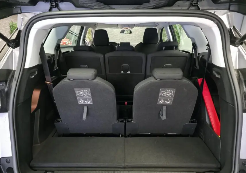 Vue arrière du coffre ouvert du Peugeot 5008 gris, montrant les sièges arrière escamotés et l'espace de chargement.