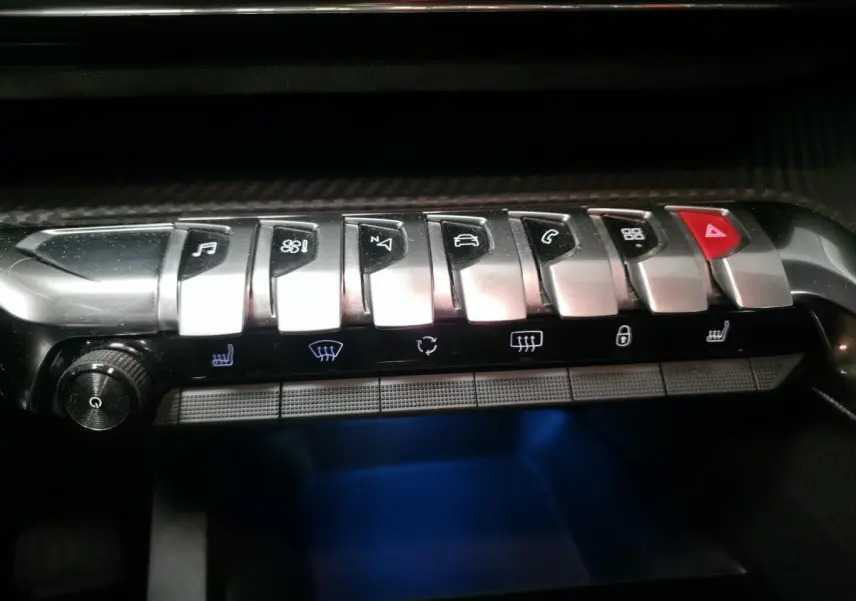 Gros plan sur la rangée de commandes chromées et boutons lumineux du tableau de bord du Peugeot 5008 gris 2020.