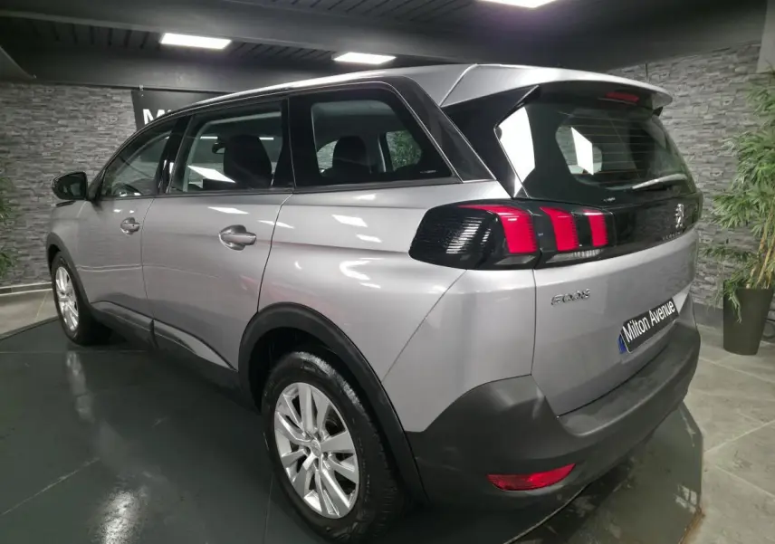 Peugeot 5008 gris métallisé vue 3/4 arrière droit, feux arrière à griffes rouges et jantes alliage 17 pouces.