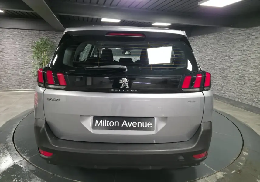 Vue arrière d'un Peugeot 5008 gris métallisé avec feux arrière à griffes rouges et lunette teintée.