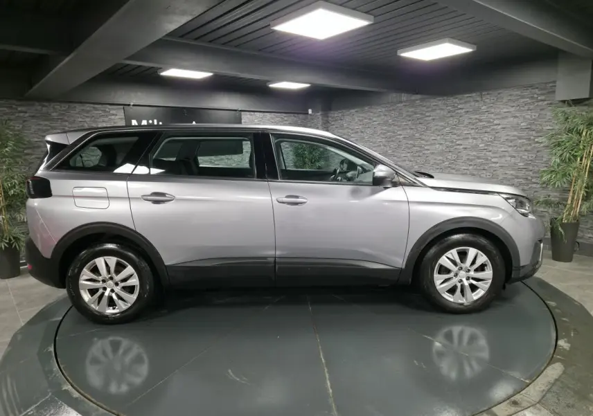 Peugeot 5008 gris métallisé vue de profil côté gauche dans un showroom avec jantes alliage 17 pouces.