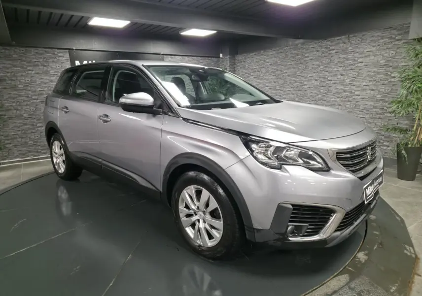 Peugeot 5008 gris métallisé vue 3/4 avant droit, avec calandre chromée et jantes alliage 17 pouces.