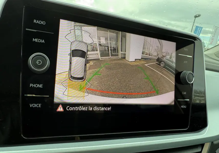 Affichage de la caméra de recul du Volkswagen T-Roc argent pyrite métallisé avec lignes de guidage vertes et rouges sur l'écran central.