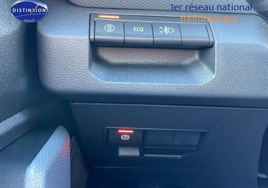 Gros plan sur les commandes de tableau de bord noir du Dacia Duster 1.2 mild hybrid 140 Journey, avec bouton ECO et frein à main électronique.