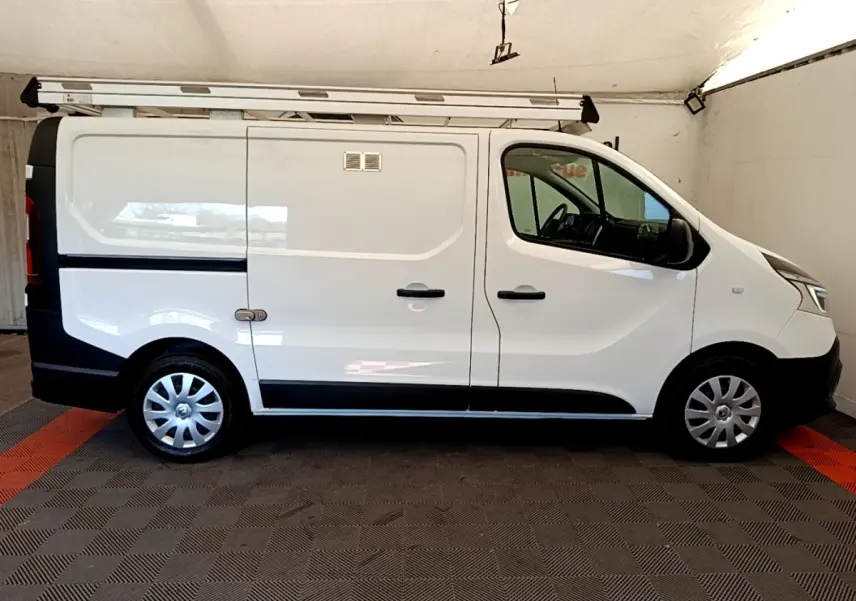 Vue de profil côté droit du fourgon blanc Renault Trafic L1H1 avec galerie de toit et jantes acier.
