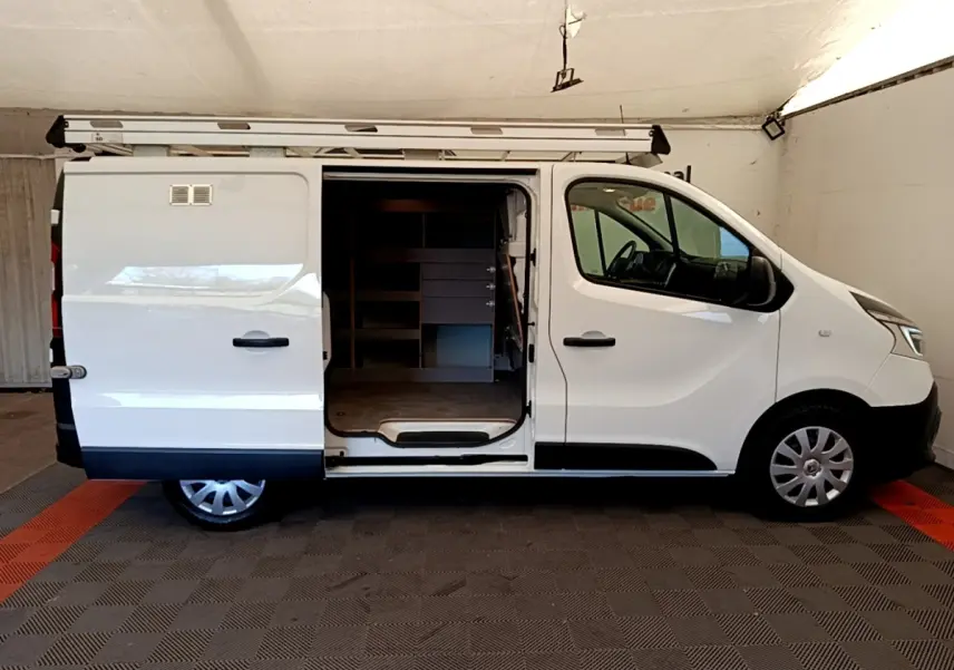 Vue latérale droite d’un Renault Trafic Fourgon blanc 2021 avec porte coulissante ouverte et galerie sur le toit.