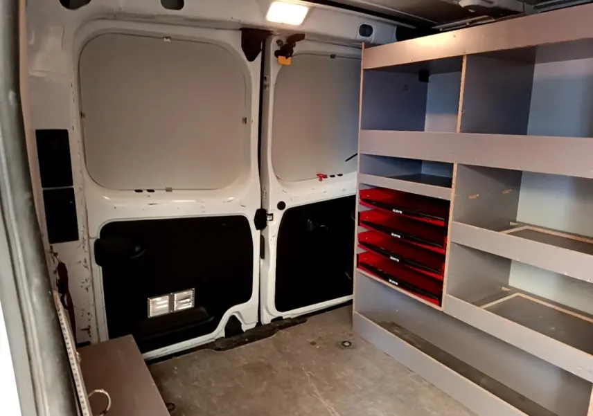 Vue intérieure arrière du Renault Trafic Fourgon blanc 2021, montrant l'aménagement avec étagères et tiroirs rouges.