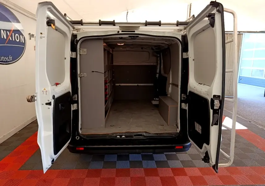 Vue arrière du Renault Trafic Fourgon blanc avec portes ouvertes montrant l'espace de chargement aménagé.