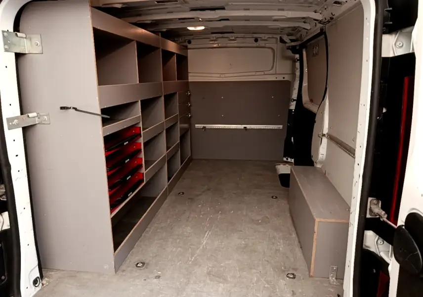 Vue intérieure arrière du Renault Trafic Fourgon blanc avec aménagements de rangement gris sur le côté gauche.