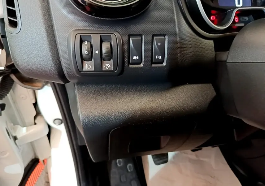 Détail du tableau de bord côté gauche du Renault Trafic Fourgon blanc, avec commandes de réglage des phares et aides à la conduite.