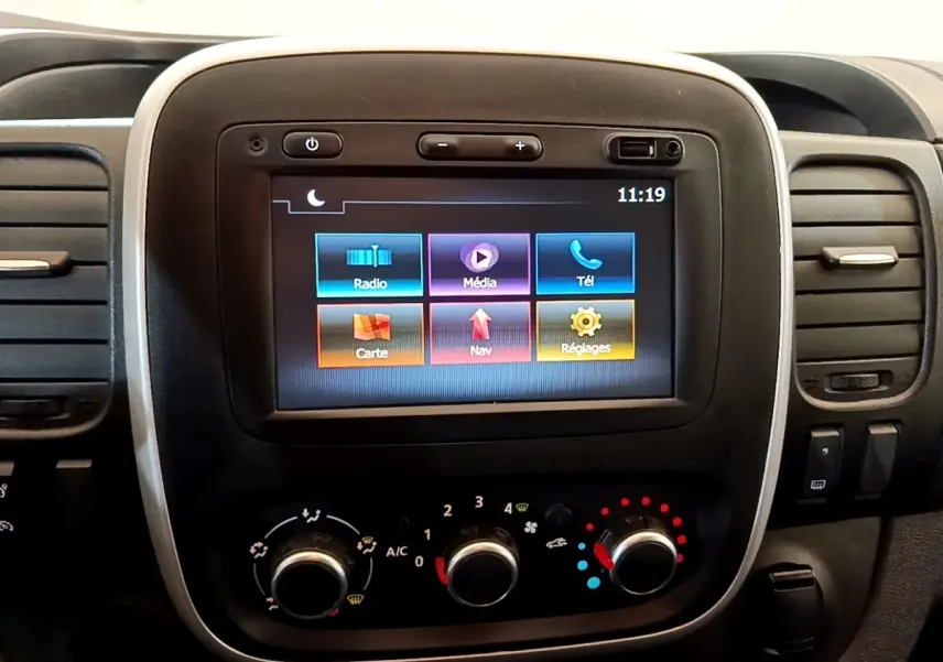 Écran tactile central avec commandes climatisation du Renault Trafic Fourgon blanc, vue intérieure frontale.