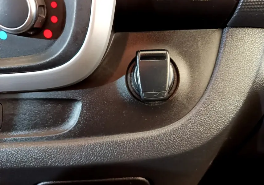 Gros plan sur la commande d’ouverture de la trappe à carburant du Renault Trafic Fourgon blanc, intérieur noir.