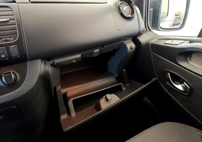 Intérieur noir du Renault Trafic Fourgon L1H1 1200 Confort 2021, vue sur la boîte à gants ouverte côté passager.